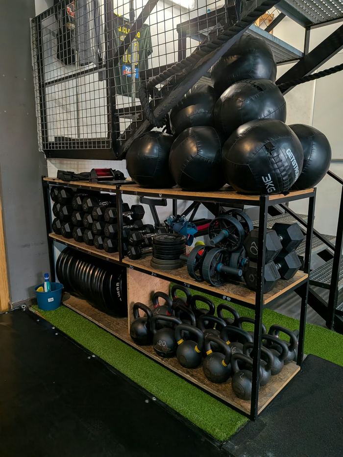 Estantería con balones medicinales, kettlebells, mancuernas y discos